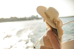 A woman wearing a large hat starring out into the ocean.