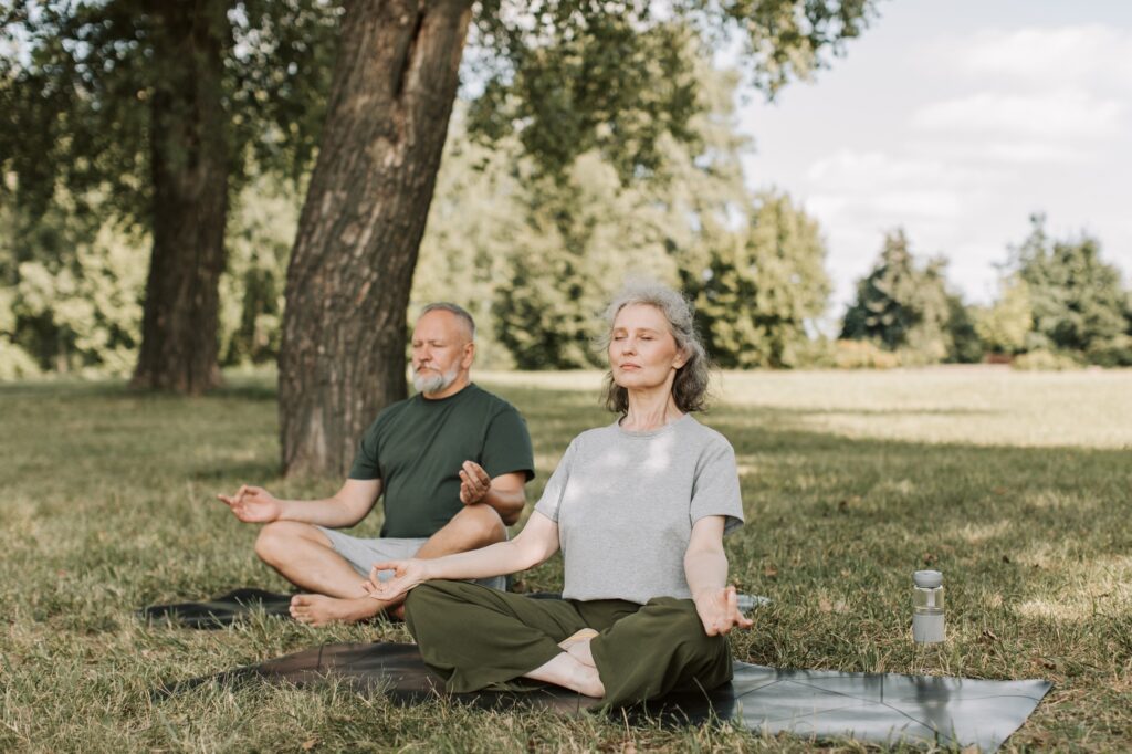 couple sitting on an open lawn practicing breathing exercises