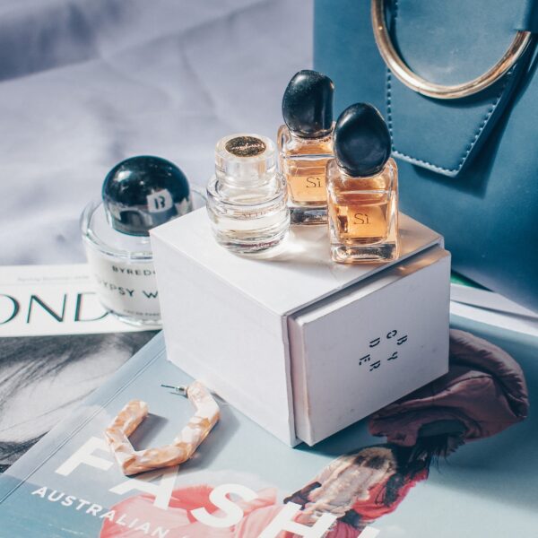 3 Perfume bottles sits on top of a fashion magazine in a luxurious manner.