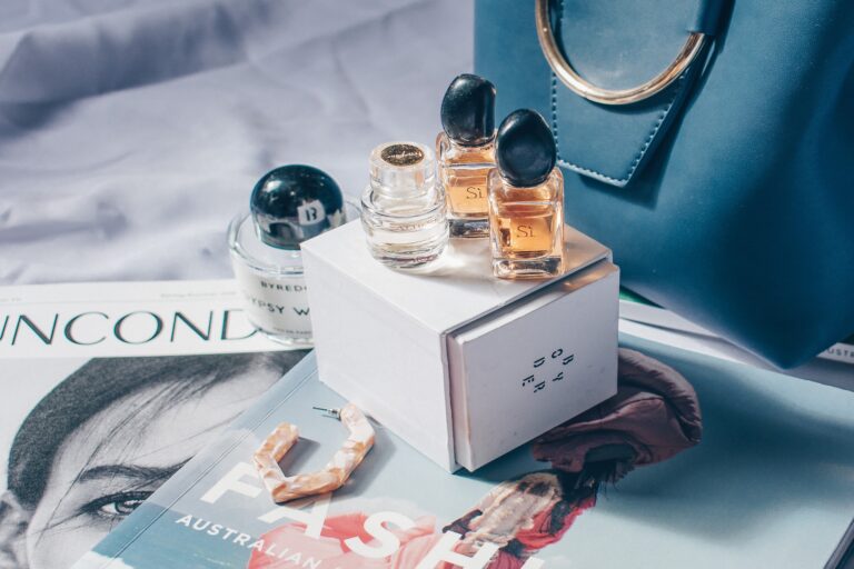 3 Perfume bottles sits on top of a fashion magazine in a luxurious manner.