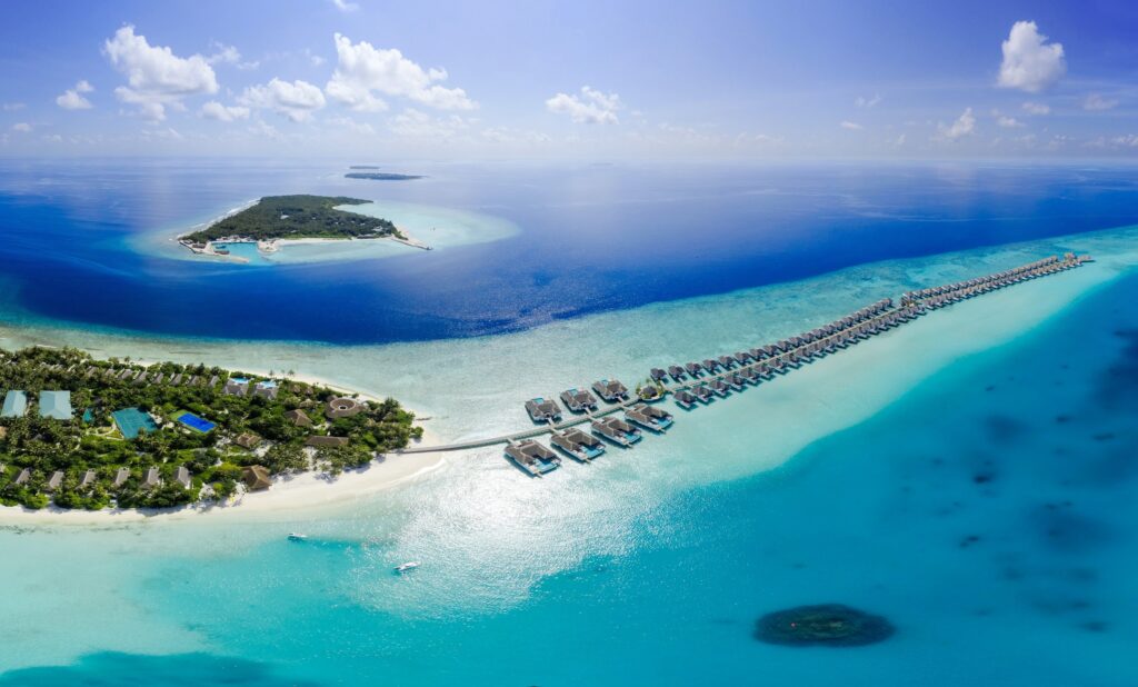 An aerial view of a white sand beach and over water resorts.